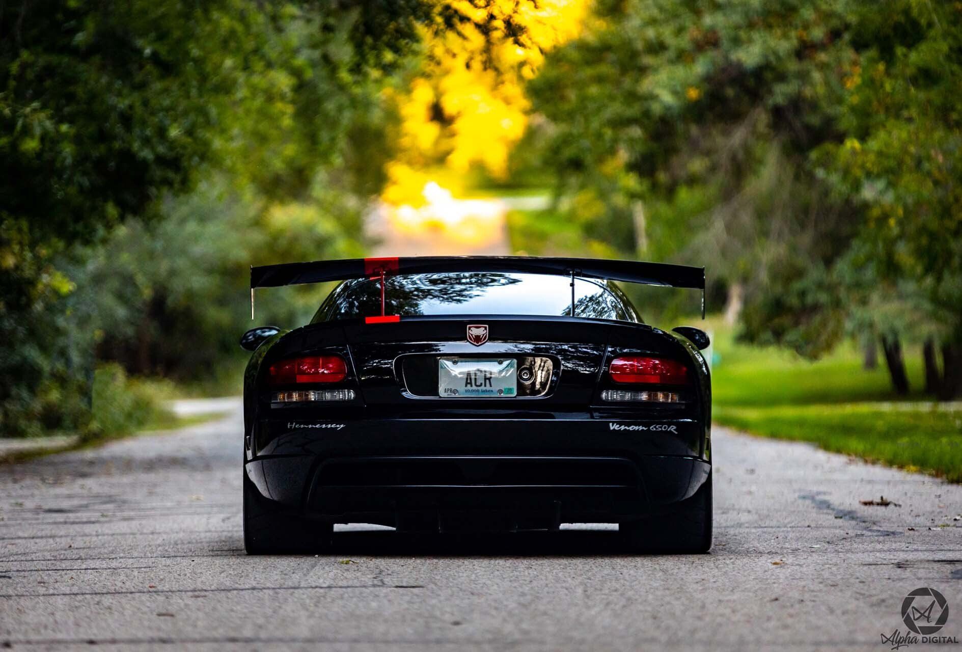 A black sports car is parked on the side of a road.