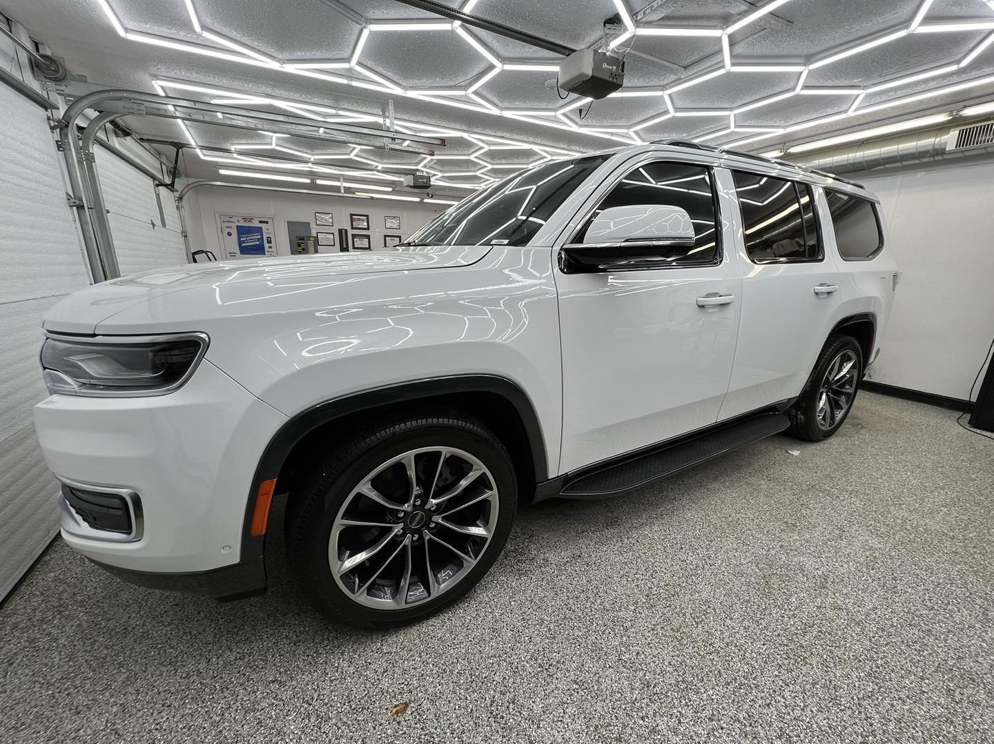 A white jeep wrangler is parked in a garage.