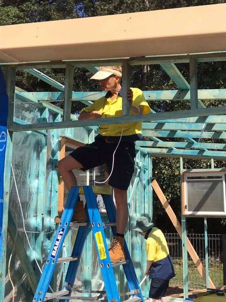 A Man is Standing on a Blue Ladder That Says Stanley on It — Dylko Electrical in Wauchope, NSW