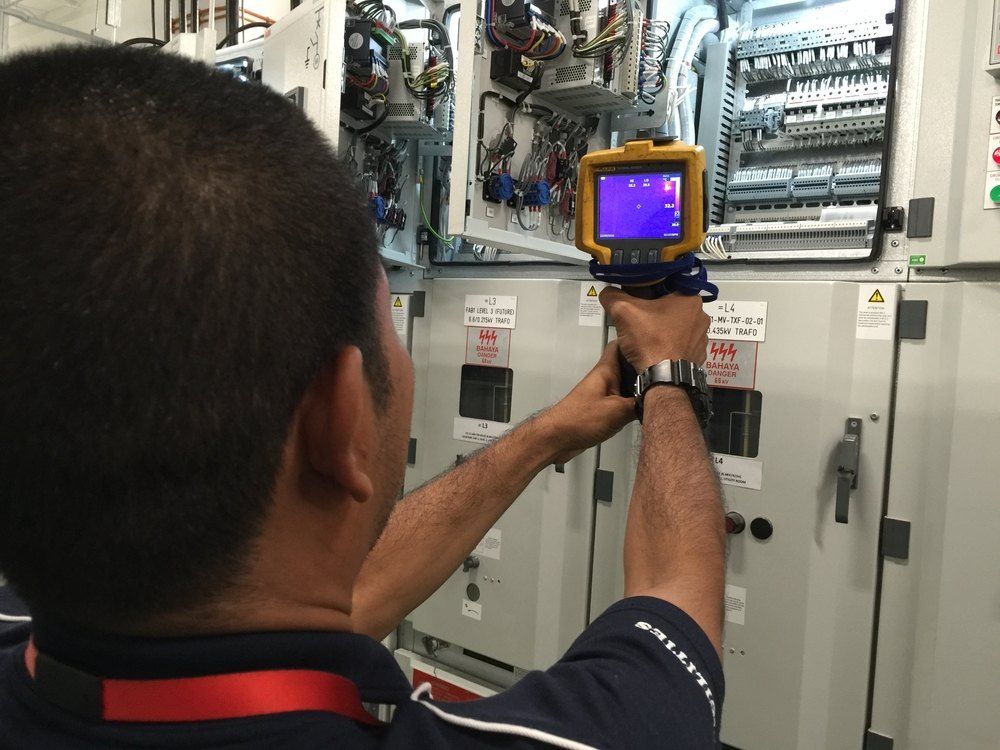 A Man is Using a Thermal Camera to Inspect a Electrical Box — Dylko Electrical in Wauchope, NSW