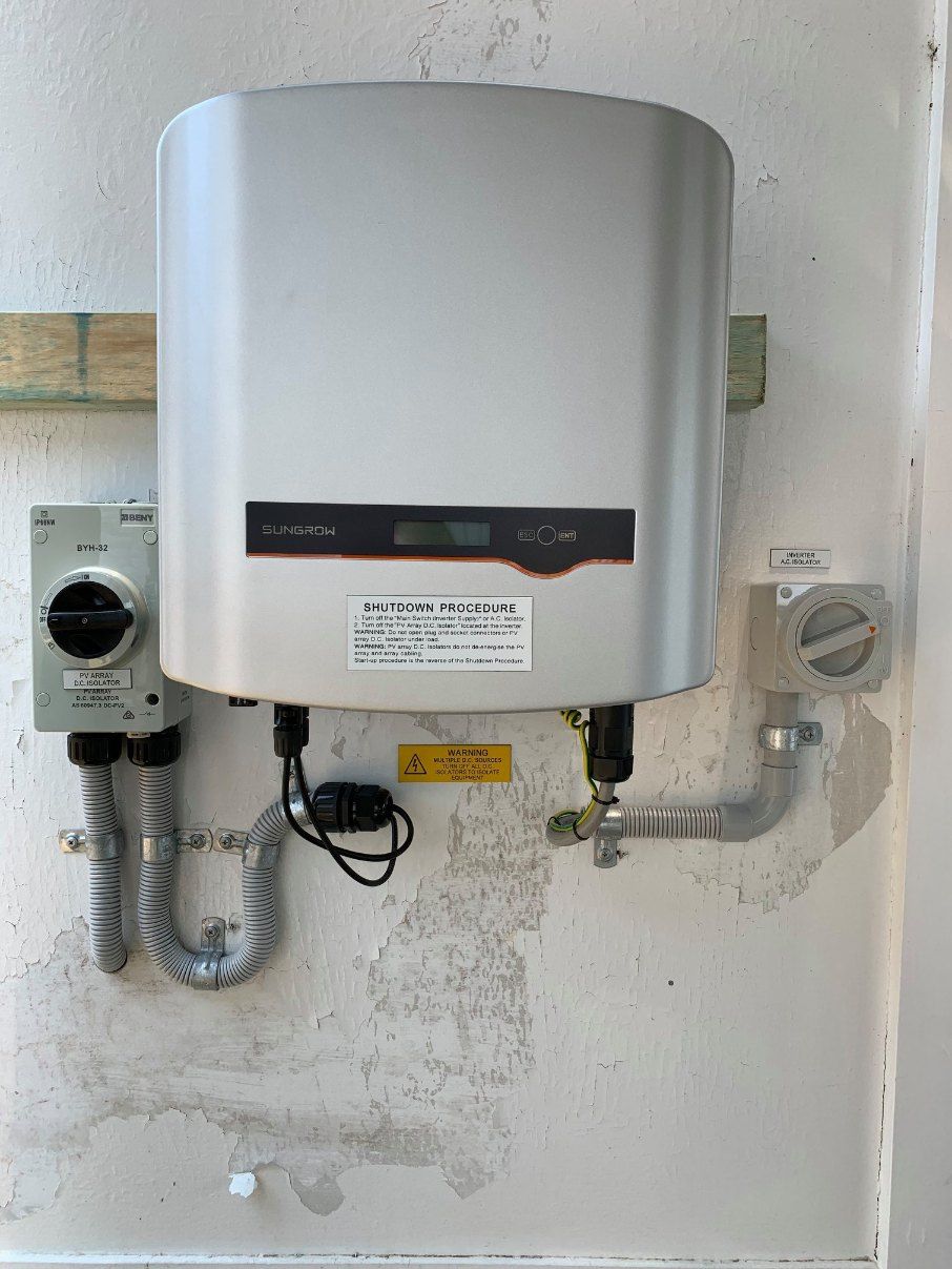 A Solar Panel Inverter is Mounted on a White Wall — Dylko Electrical in Wauchope, NSW