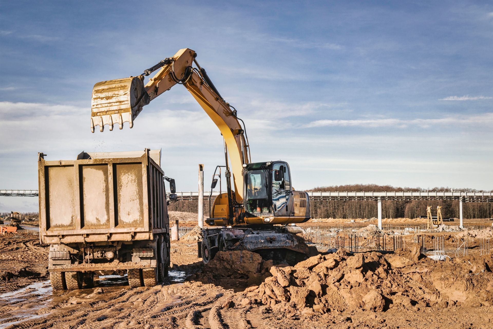 An excavator is loading dirt into a dump truck at a construction site.