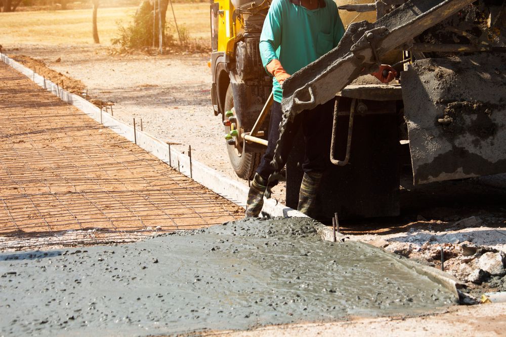 A man is pouring concrete on a sidewalk.