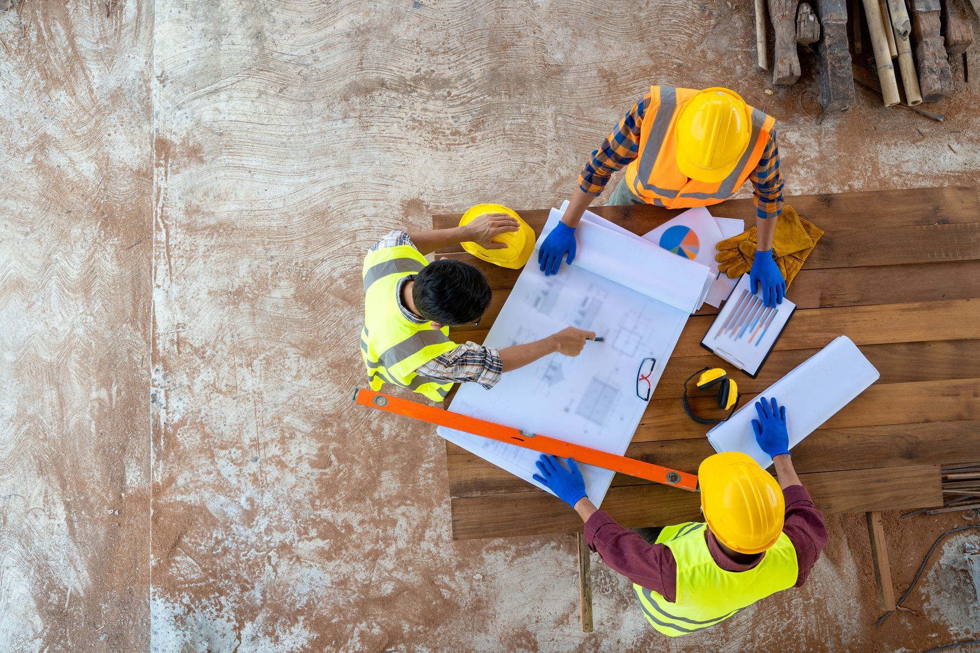 A group of construction workers are sitting around a table looking at a blueprint.