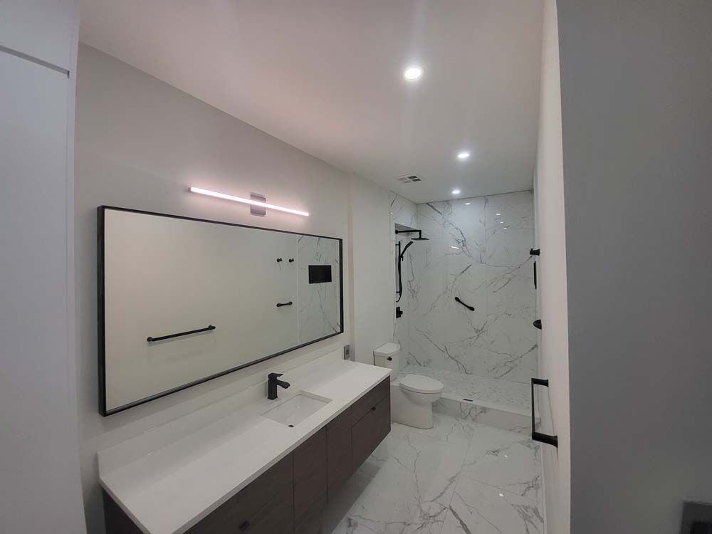 A bathroom with a sink , toilet , shower and mirror.