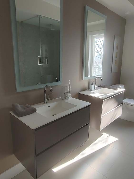 A bathroom with two sinks , two mirrors and a toilet.