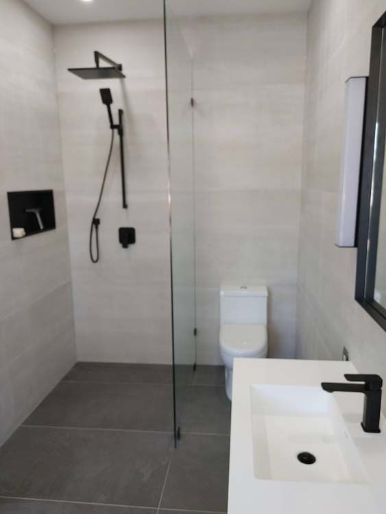 A bathroom with a toilet a sink and a walk in shower