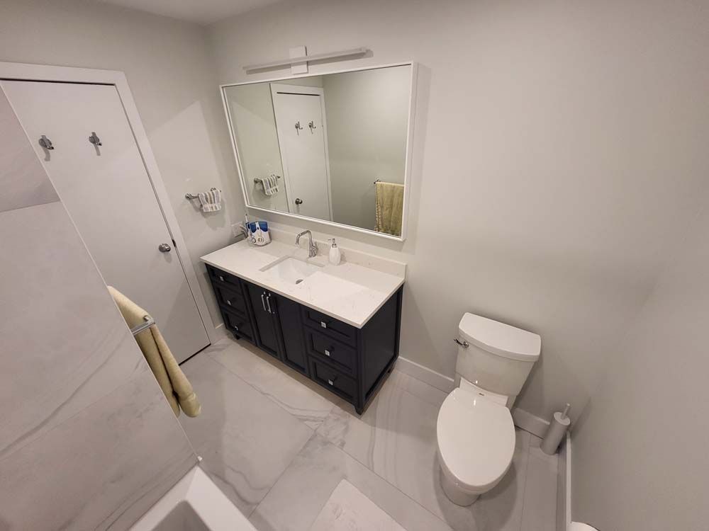 A bathroom with a toilet , sink and mirror.
