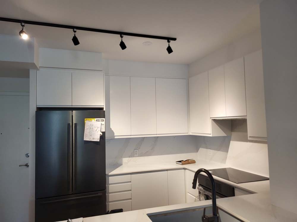 A kitchen with white cabinets and a black refrigerator