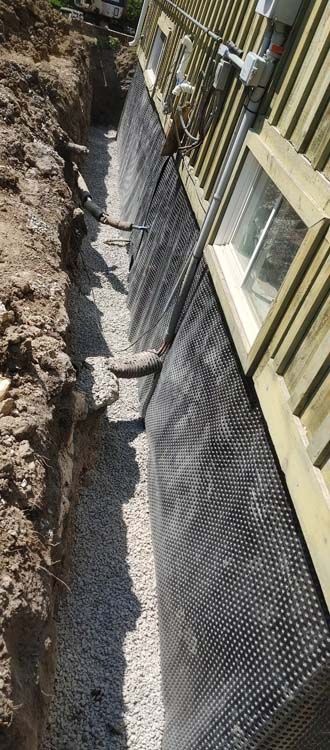 A drainage system is being installed on the side of a house.