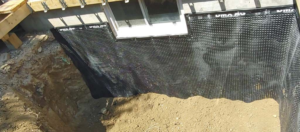 A drainage system is being installed on the side of a house.