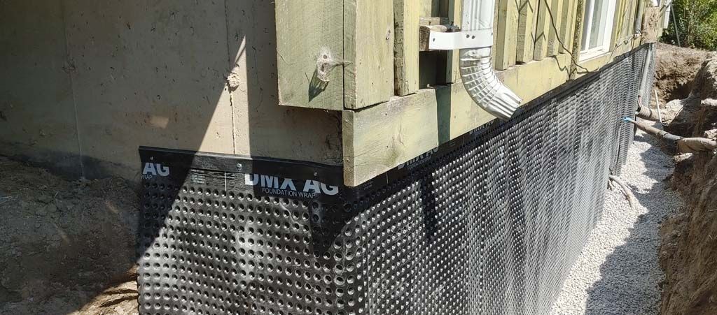A drainage system is being installed on the side of a house.
