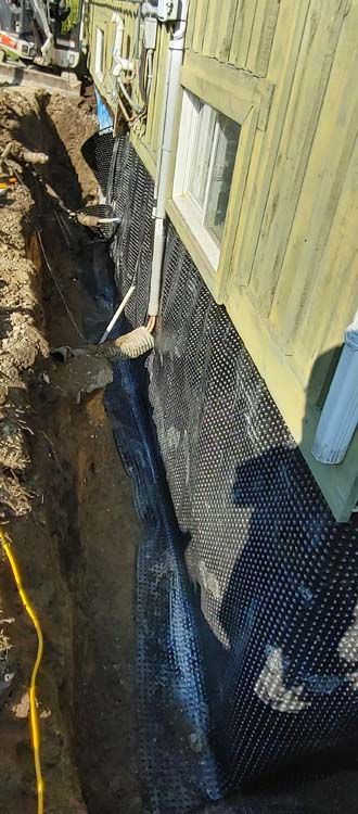 A house is being remodeled and a trench is being dug in front of it.