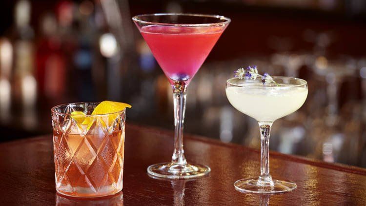 Three different types of cocktails are sitting on a bar.