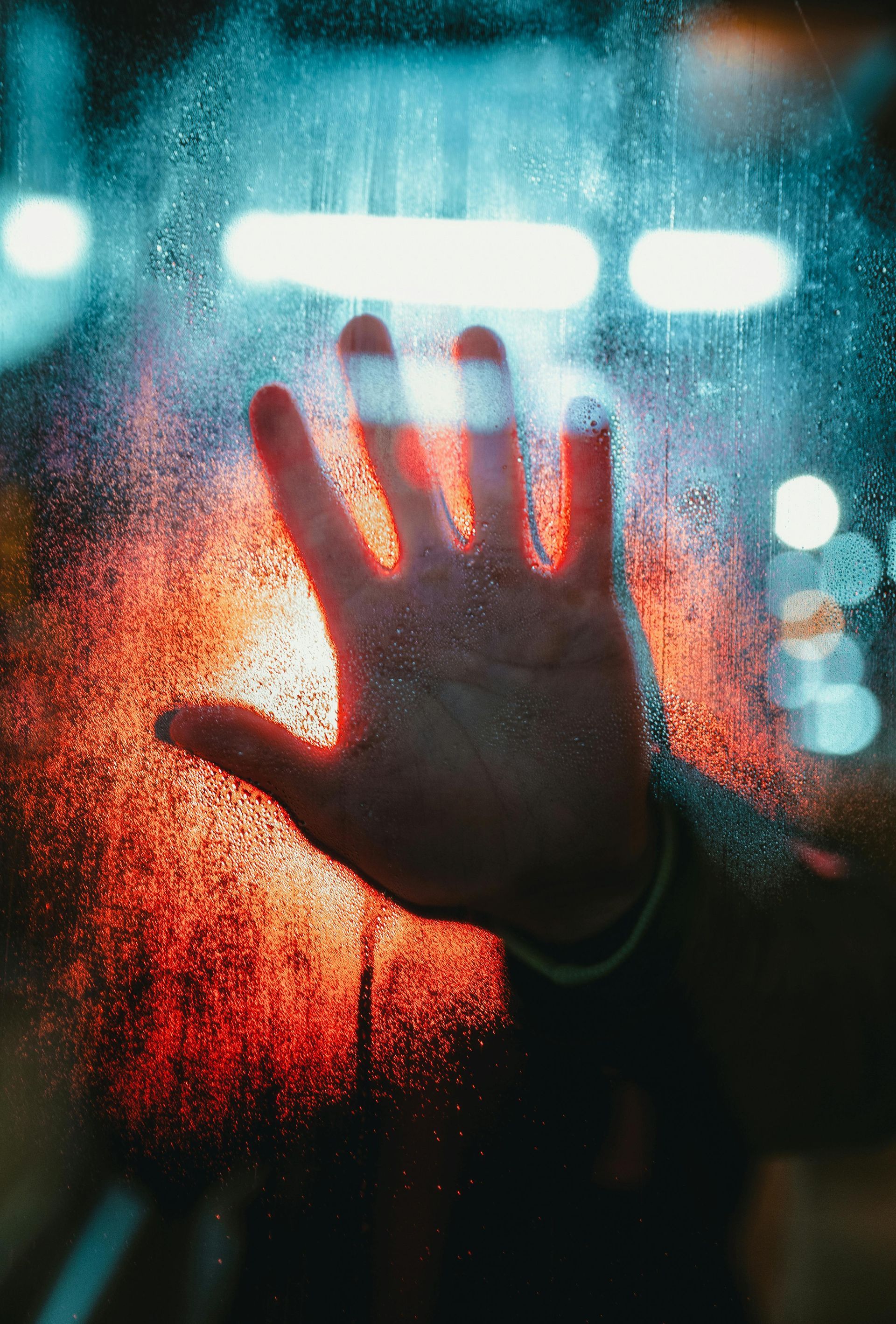 a hand against a wet window