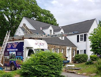 a roofing truck is parked in front of a house .