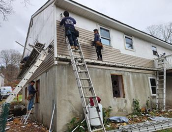 a group of people are working on the side of a house .