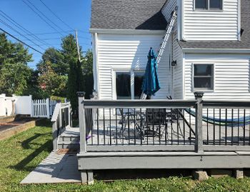 a white house with a gray deck and a blue umbrella .