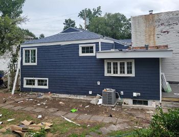 a blue house with white trim and windows is being remodeled .