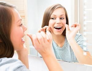 A girl in a mirror  flossing - Lincoln, NE - Blome Family Dentistry