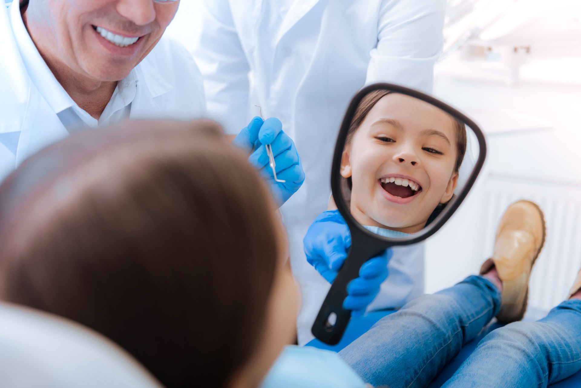 Joyful girl smiling in the dentist's office mirror, showcasing care from a trusted family dentist in