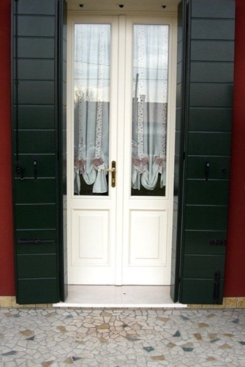 una porta finestra bianca con persiane verdi
