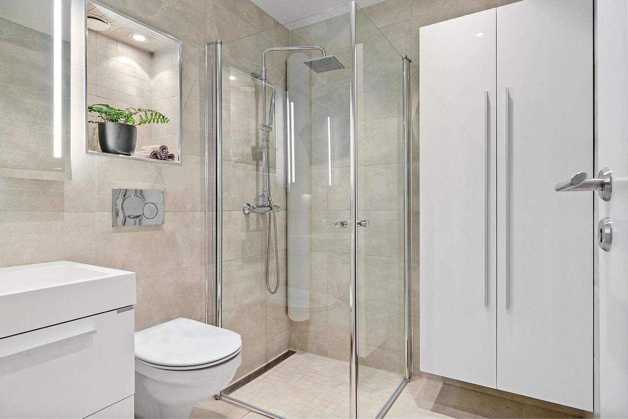 Bright, white themed bathroom with cupboard, enclosed shower and wall-mounted toilet