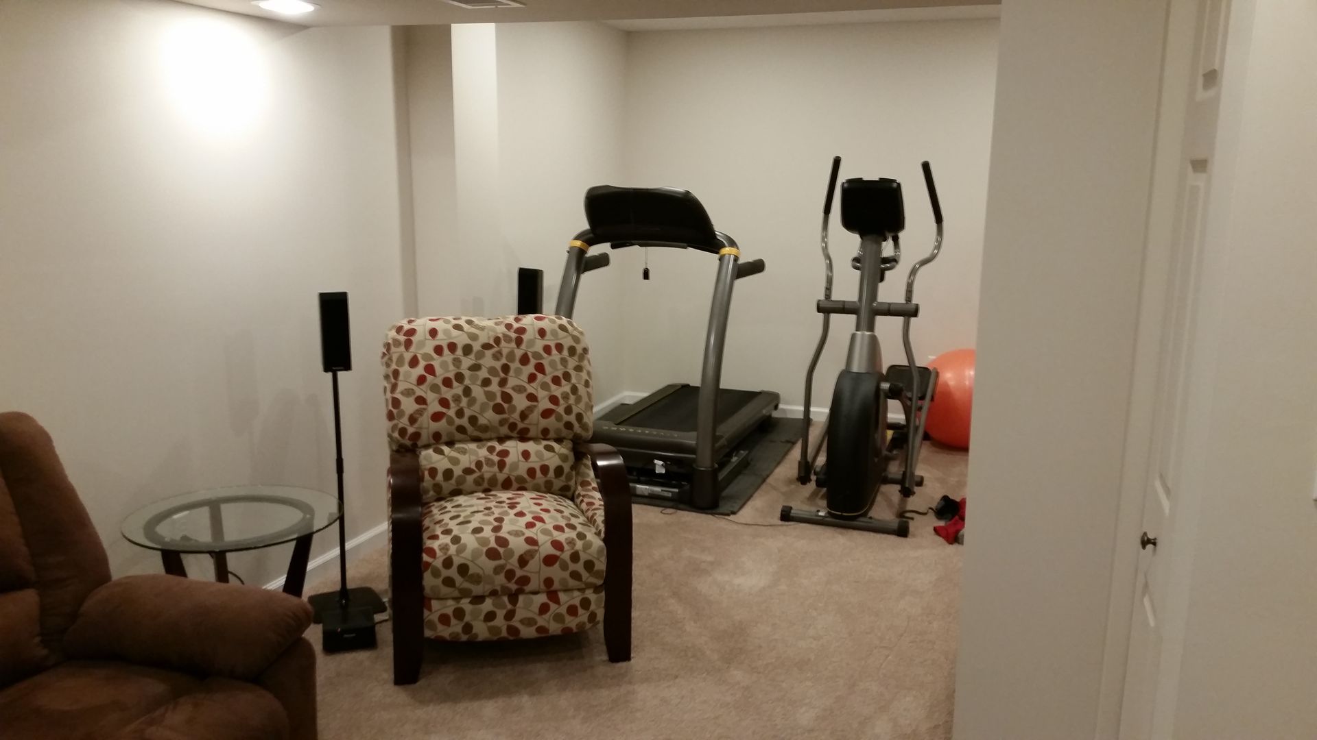 A living room with a treadmill and an elliptical