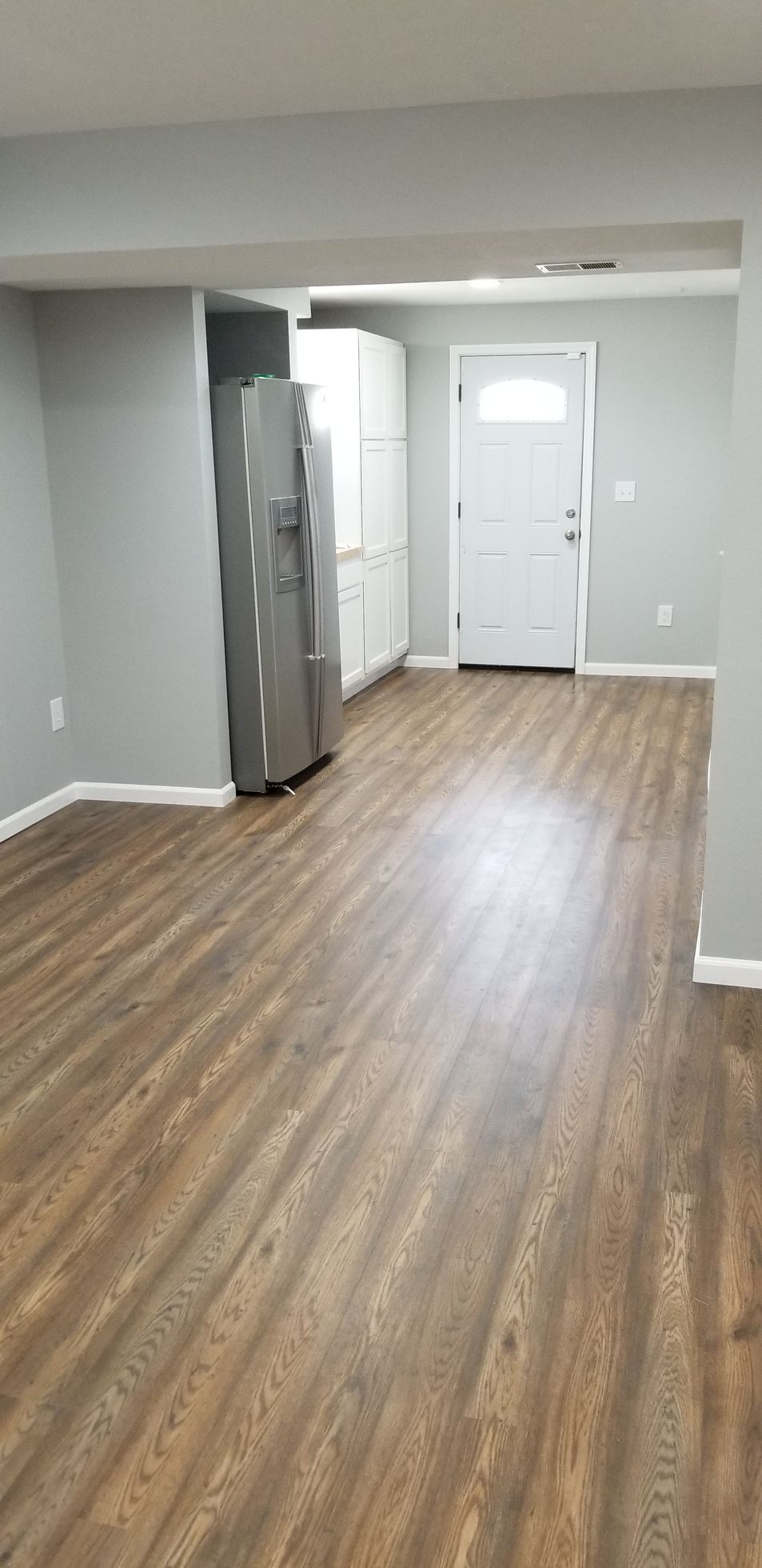 A living room with hardwood floors and a refrigerator.