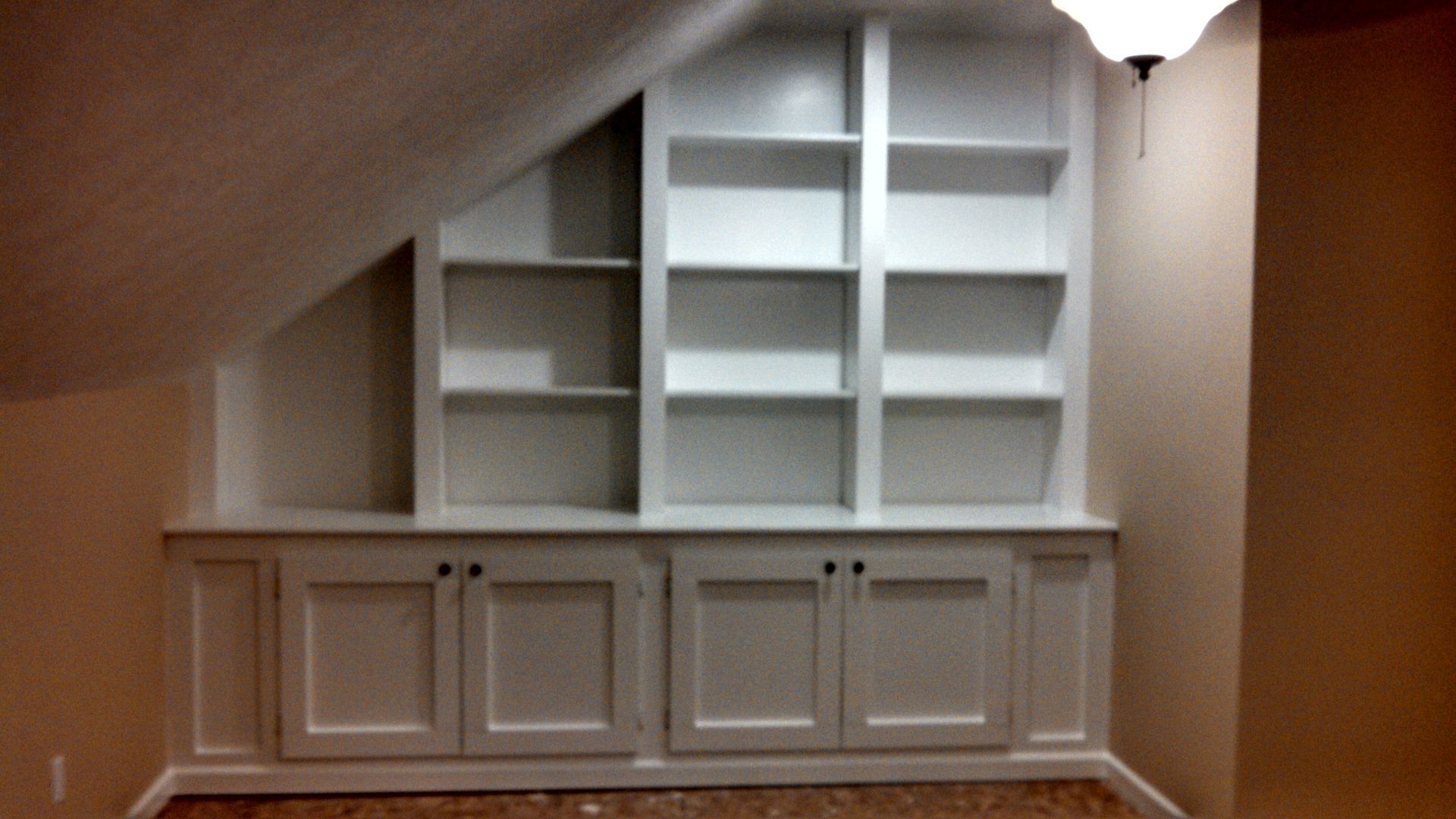 A room with a slanted ceiling and white shelves