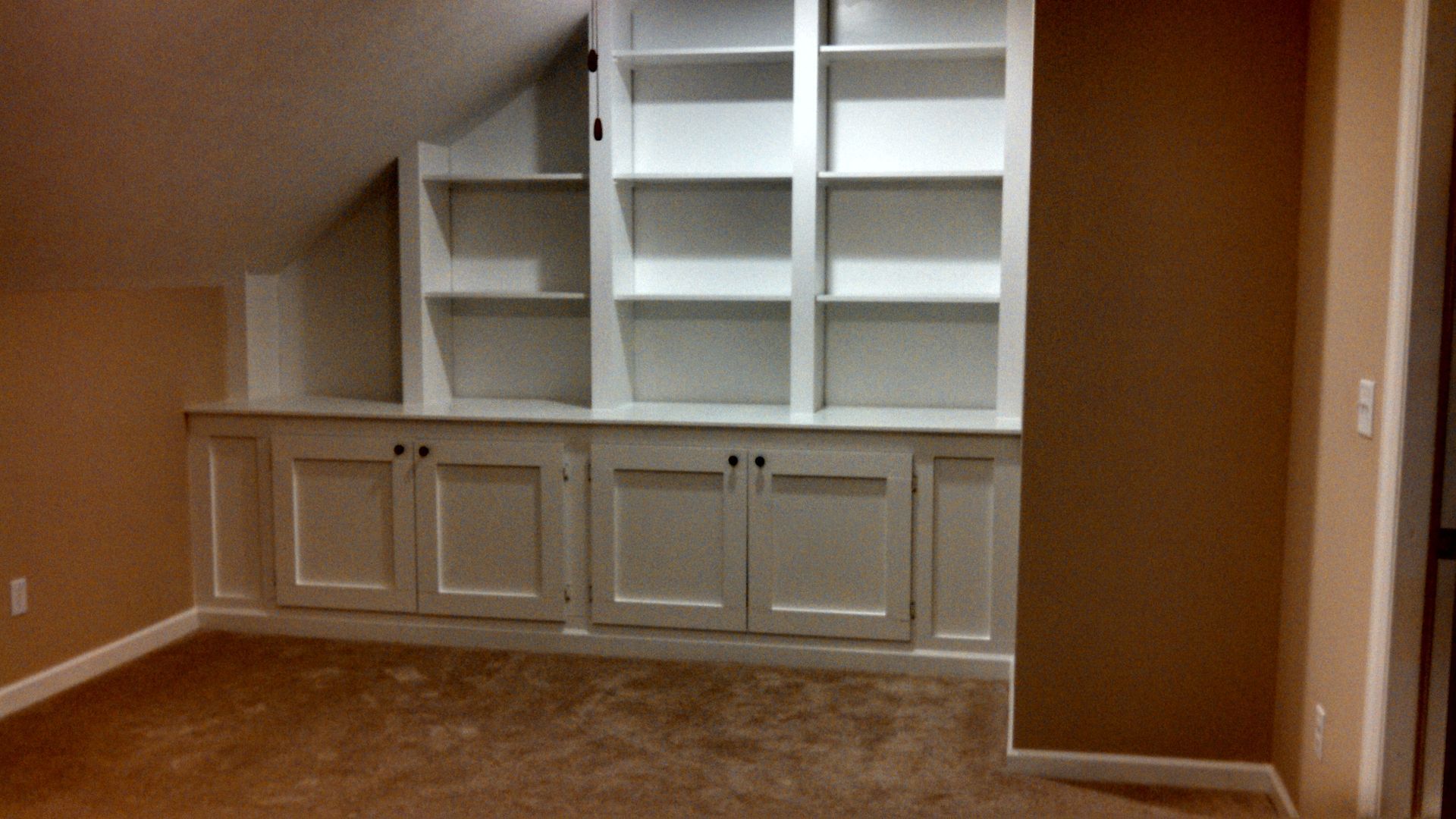 A corner of a room with shelves and cabinets