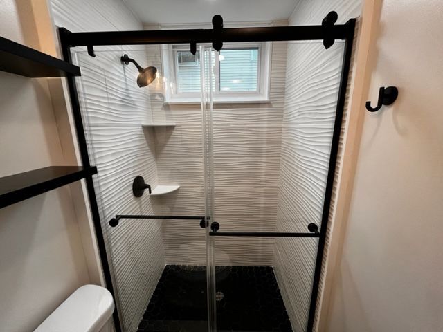 A bathroom with a sliding glass shower door and a toilet.