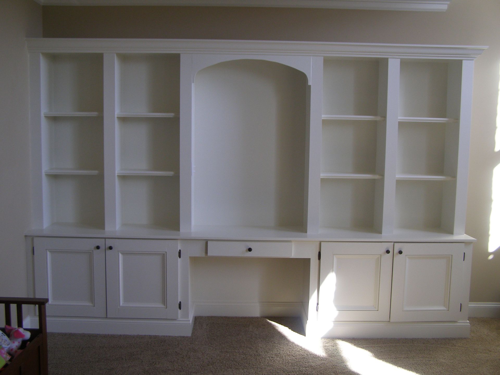 A large white bookshelf with a desk underneath it
