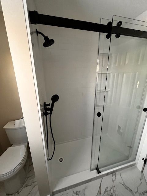 A bathroom with a sliding glass shower door and a toilet.