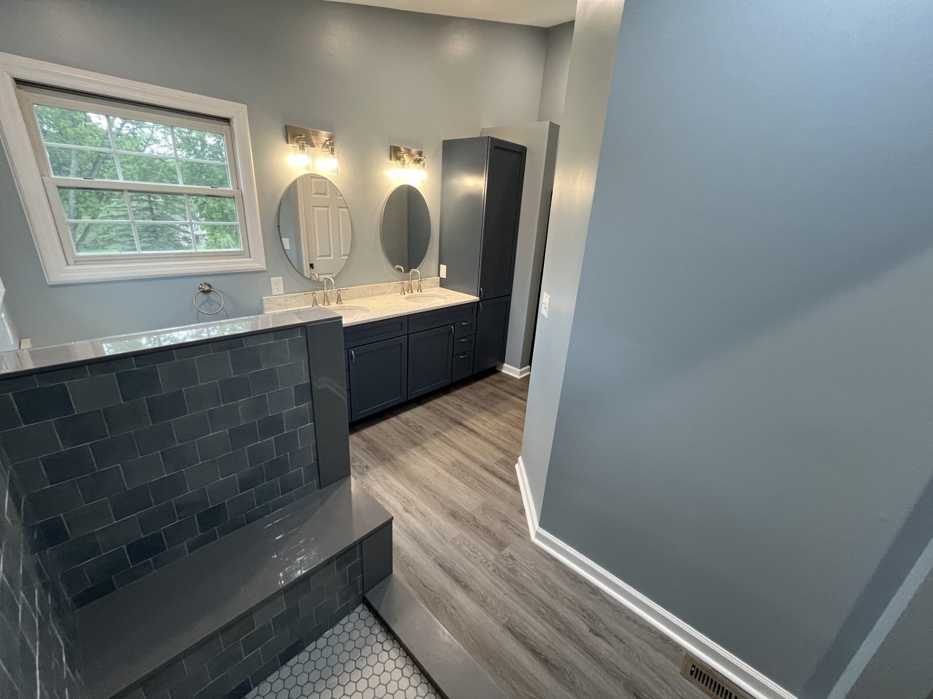 A bathroom with two sinks , two mirrors and a window.