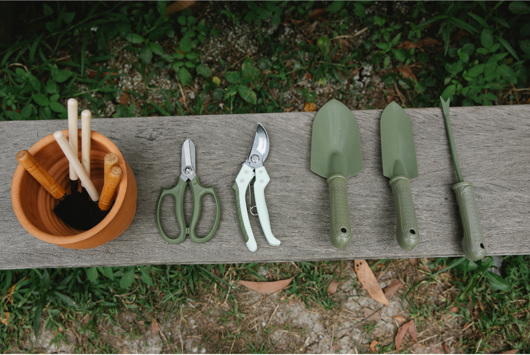 A set of gardening tools sitting on top of a wooden bench.