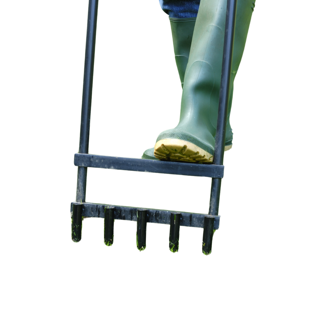 A person wearing green boots is using a lawn rake