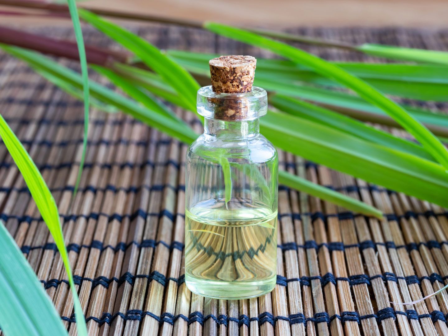 A small bottle of essential oil is sitting on a bamboo mat.