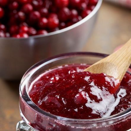 A jar of lingonberry sauce with a wooden spoon in it