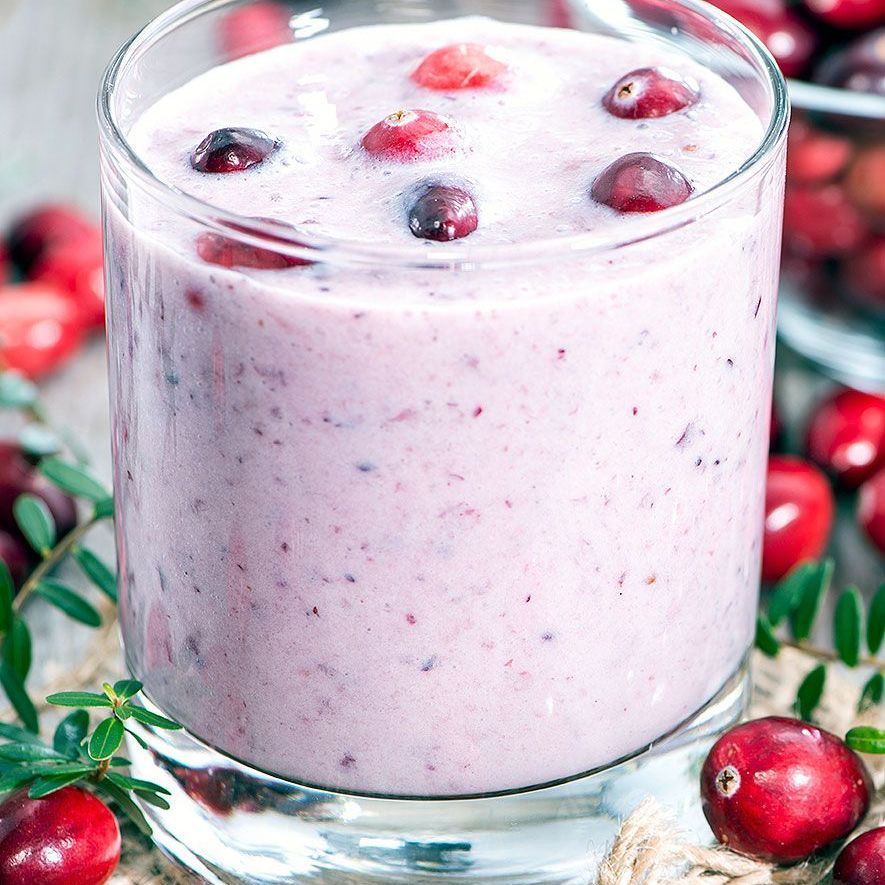 A lingonberry smoothie in a glass with lingonberries on top.