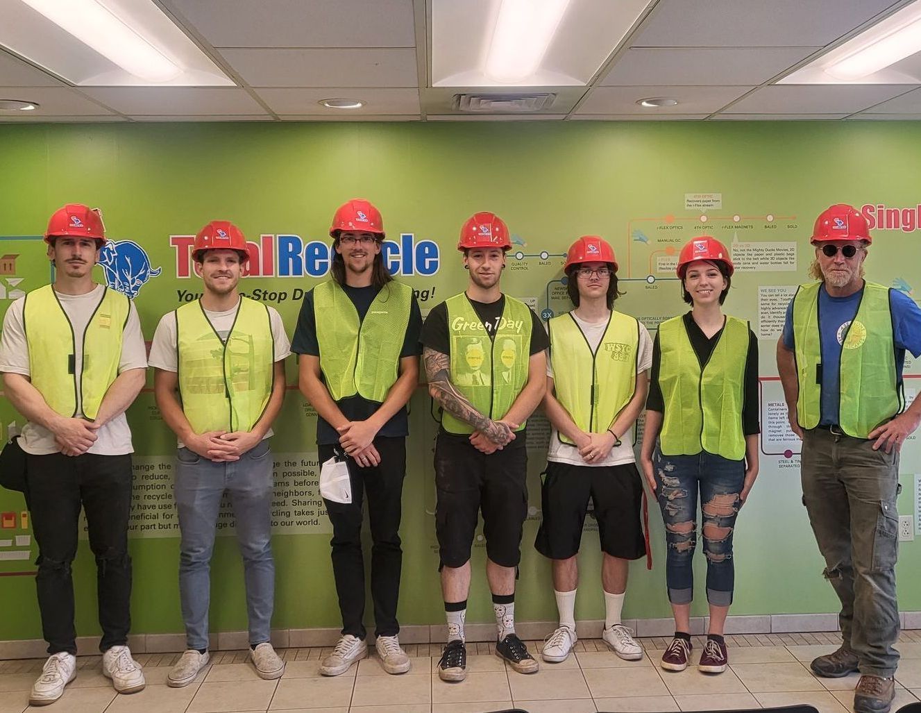 the 4 Seasons crew in hardhats and vests, standing in front of the Total Recycle recycling diagram