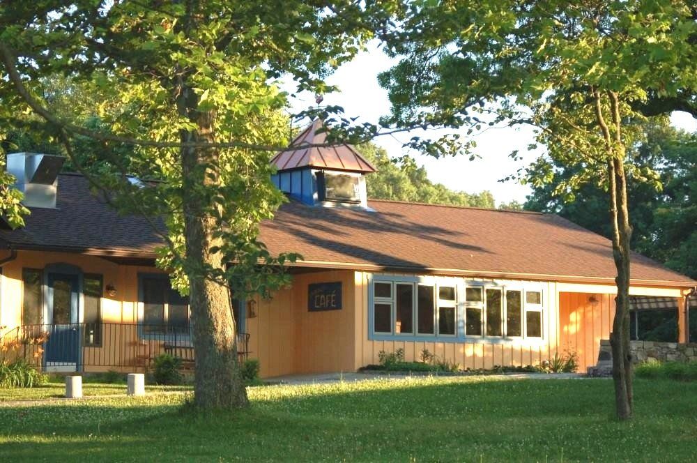 A house with a brown roof and a blue porch is surrounded by trees