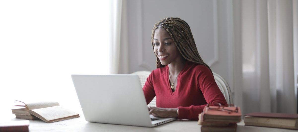 A group of people are sitting around a table with laptops.