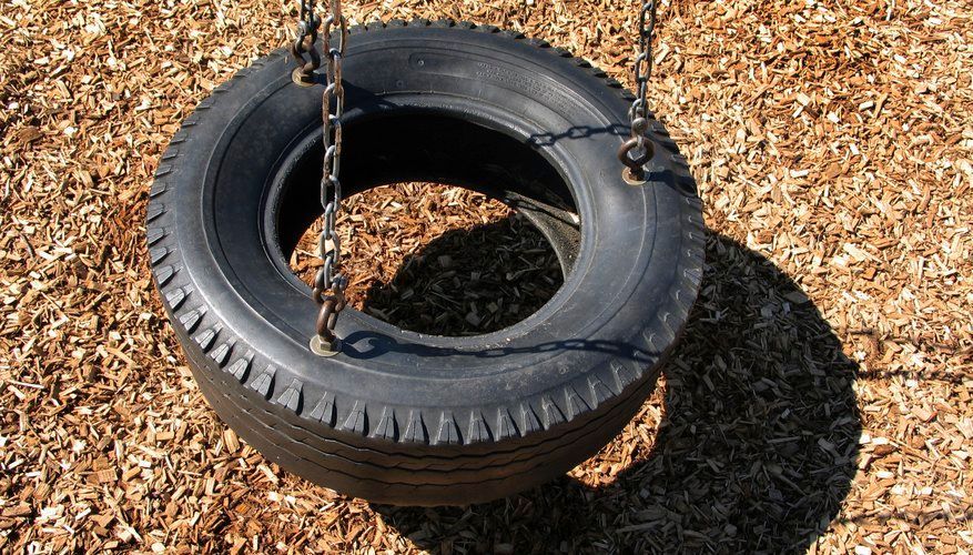 A tire swing is hanging from chains on the ground