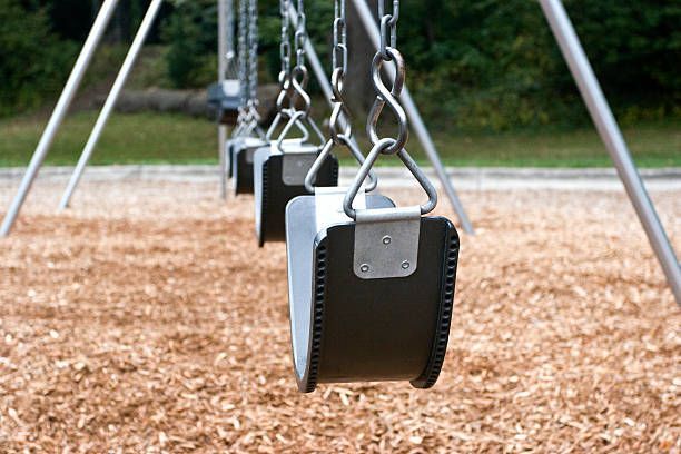 A row of swings hanging from chains in a park.