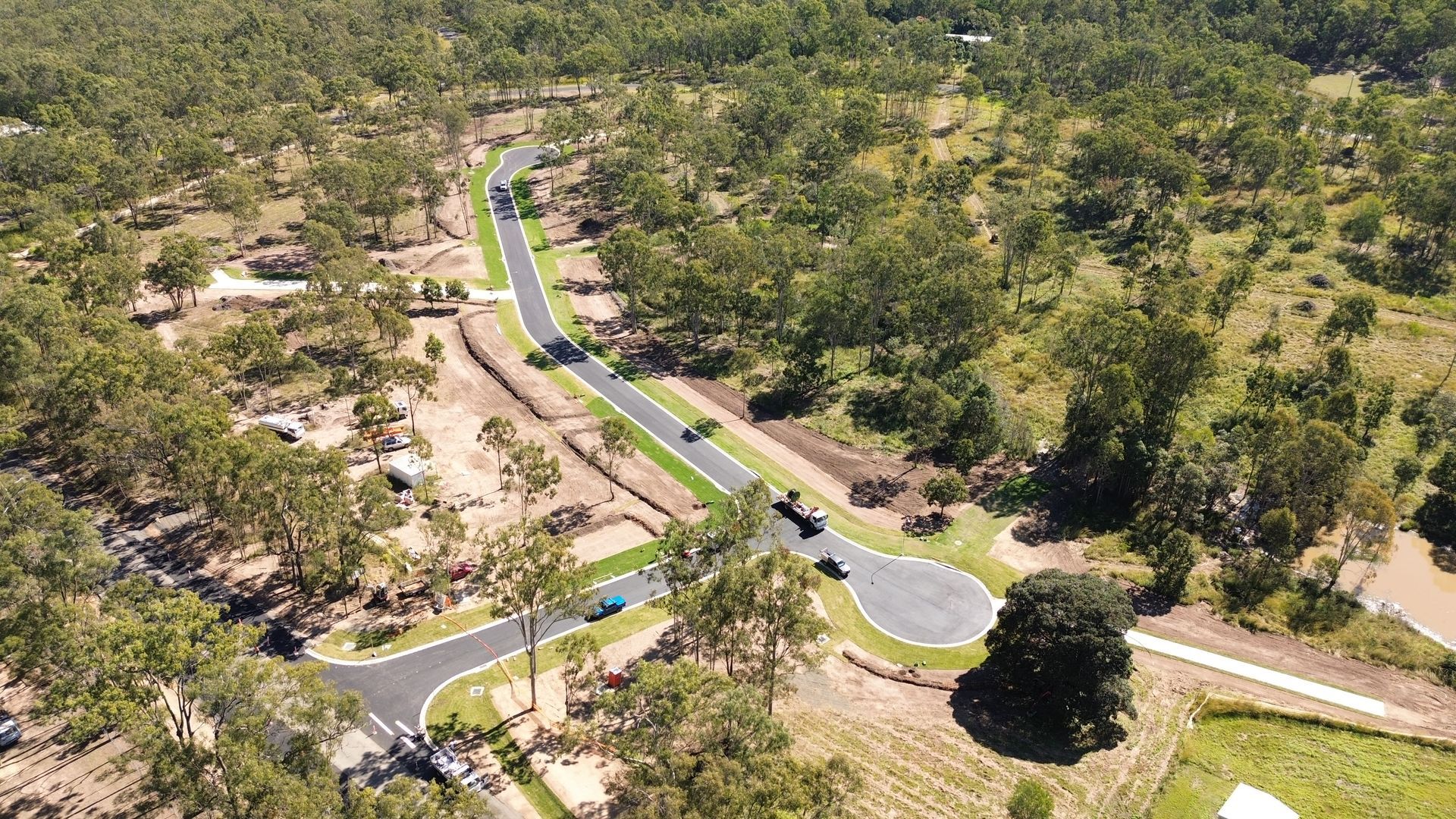 An aerial view of a road surrounded by trees and grass.