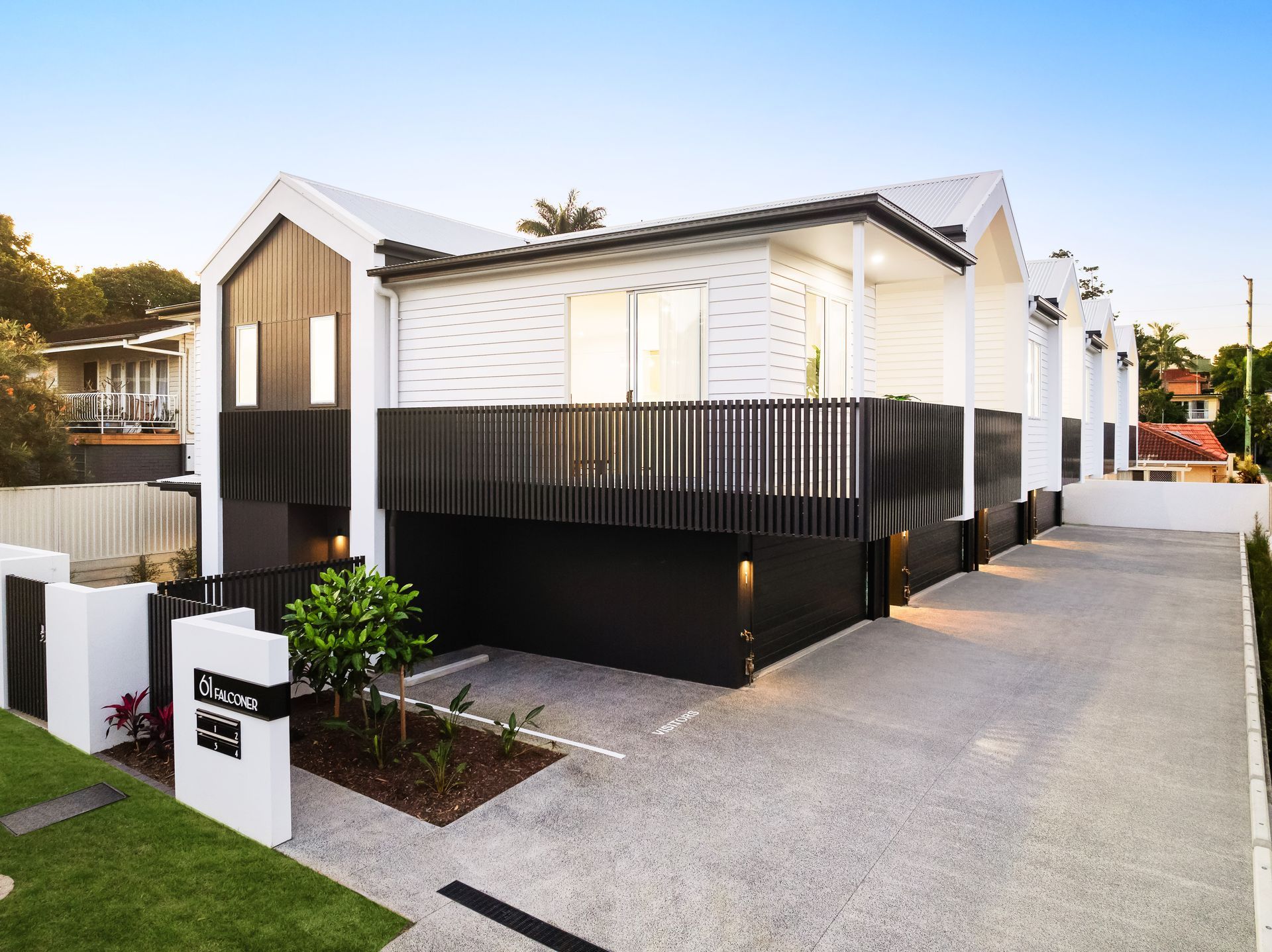 A white and black house with a driveway in front of it