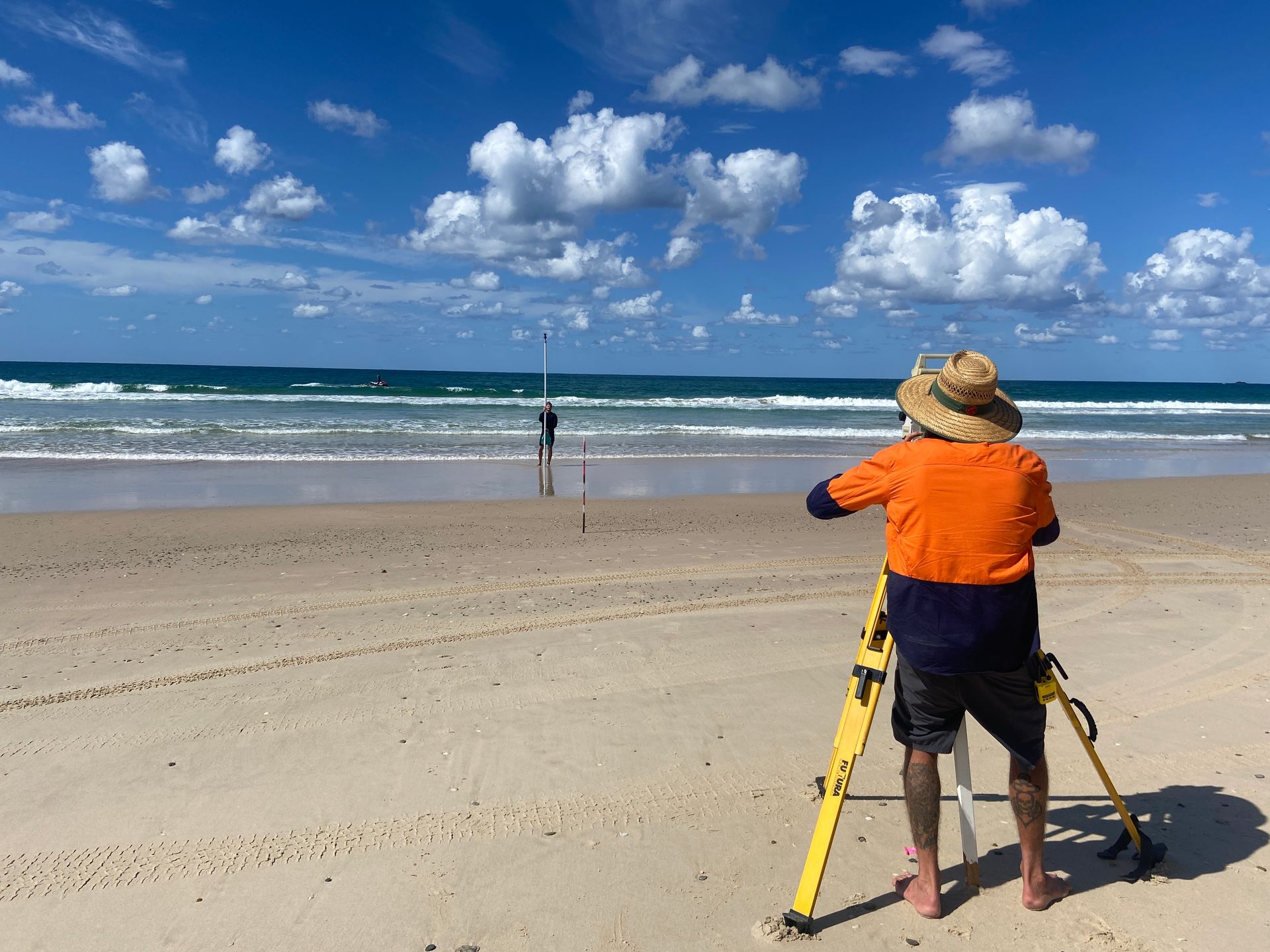 A man is standing on a beach looking at the ocean.