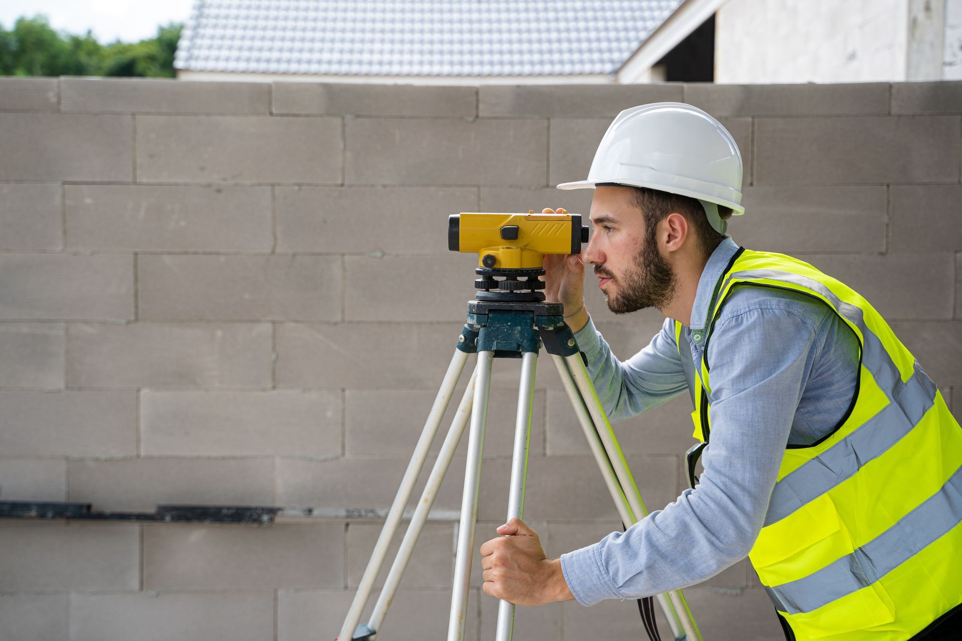 A property land surveying professional using levelling equipment on a construction site.