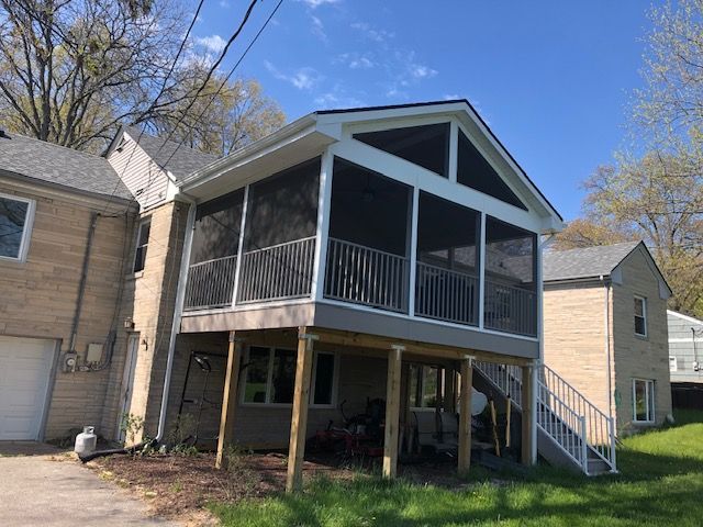 A house with a screened in porch and stairs.